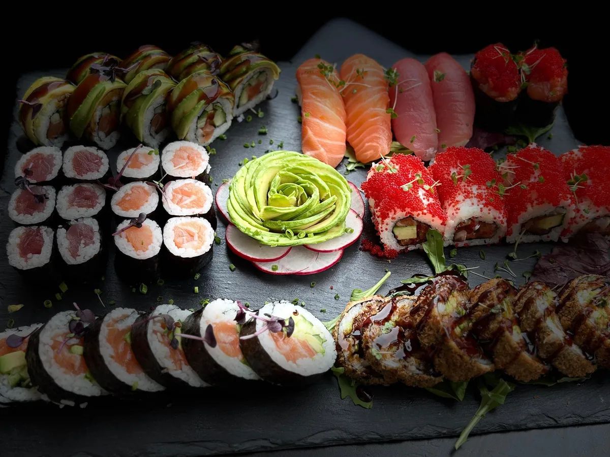 Sushi-Platte mit Nigiri, Maki, Dragon Rolls, Tobiko-Rolls, Crunchy Rolls und Avocado-Rose